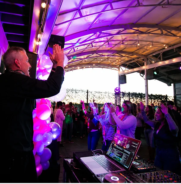 DJ entertaining crowd at outdoor party.